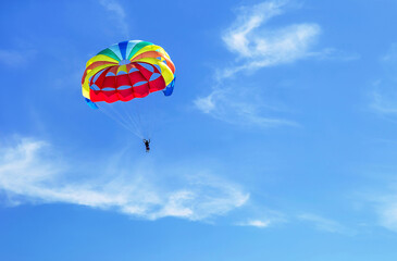 Fototapeta na wymiar Parachute jumping. Colorful parachute is in the sky, under the clouds. Copy space