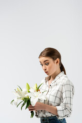surprised attractive girl posing like puppet with flowers isolated on grey
