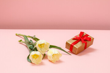 Gift box with tulip flowers on a pink background.