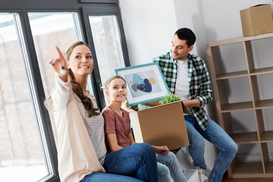 mortgage, family and real estate concept - happy mother, father and little daughter with stuff in boxes moving to new home