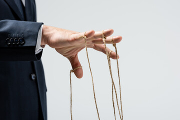 cropped view of puppeteer with strings on fingers isolated on grey