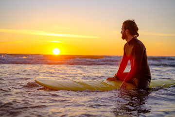 Surfer sitting on surfboard in sea