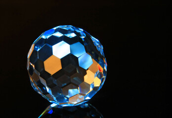 Faceted glass sphere on a black reflective surface