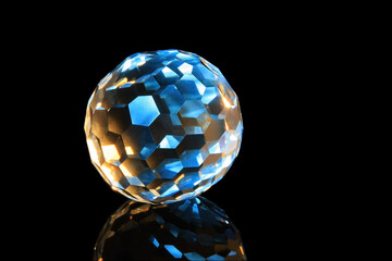 Faceted glass sphere on a black reflective surface