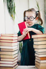 Little cute expert in books. Young librarian girl hold library book