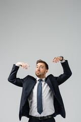 businessman marionette in suit with raised hands isolated on grey