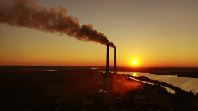 Industrial landscape from drone view. Factory chimney piping smoke into the air pollution during sunset