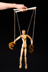cropped view of puppeteer holding wooden marionette on strings with currency signs isolated on black