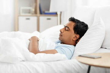 people, bedtime and rest concept - indian man sleeping in bed at home