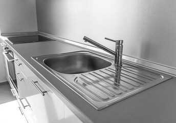 Kitchen sink and faucet on an empty kitchen worktop.