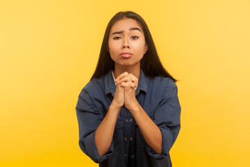Please! Portrait of imploring girl in denim shirt asking heartily and holding hands in prayer...