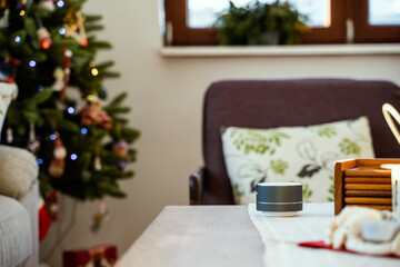 Fototapeta na wymiar Smartvoice ai speaker with christmas tree in background. Smart home concept during Christmas holiday winter time