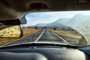 View from car window on the road and strange landscape with a valley, mountains and blue sky with clouds. Landscape through windscreen in Cappadocia in Turkey