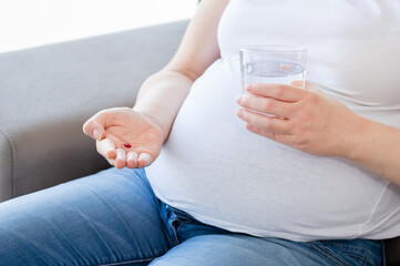 Pregnant woman with pills with iron FE ferrum element in hand. Dietary supplements. Vitamin capsules