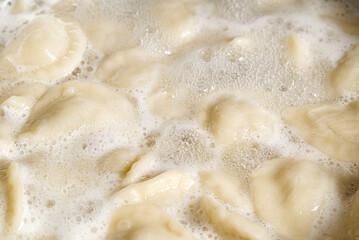 cooking dumplings in a pan with water, Meat in dough rolls. Top view.