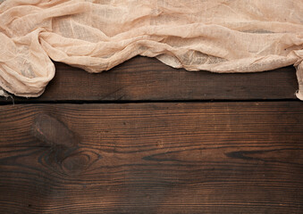 gray kitchen textile towel folded on a brown wooden table from old boards, top view, empty space