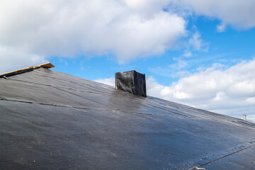 close up view of standard waterproofing layer of black color applied to protect roof and chimney from water penetration