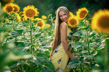 Beauty Girl Outdoors enjoying nature. Beautiful Teenage Model girl with long healthy hair posing on the Sunflower Spring Field, Sun Light. Glow Sun. Hat. Free Happy Woman. Toned in warm colors