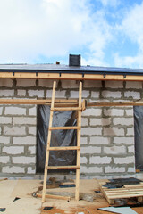 close up view of scaffolding and house under construction with holders for gutters water drainage system of roof