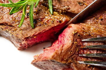 Medium rear beef steak. White plate with Piece of beef steak on fork.