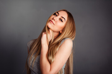 A girl with blue eyes looks piercingly into the frame, wrapping her hair in a gray background