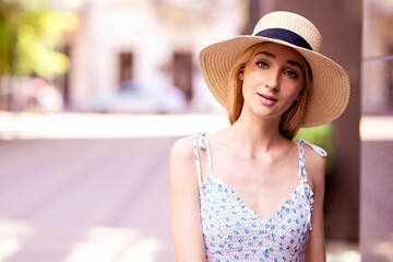 Beautiful young woman straw hat and smiling while standing on the street