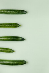 Cucumbers on a light green background. The view from the top. Space for text.