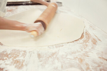 Baker's hands rolling bread in kitchen