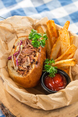 Barbeque Pulled Pork Sandwich with tomato Sauce and Fries on fabric napkin