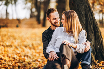 Man and woman hugging and smiling on the background of autumn trees.