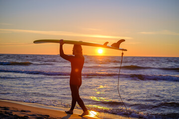 Surfer carrying surfboard near sea - Powered by Adobe