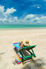 Fototapeta na wymiar Woman on a sun lounger at the white sand tropical beach