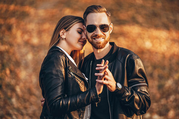 Beautiful young couple walking in the autumn park on a sunny day. They hug and smile, enjoy a walk