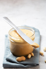 Peanut butter in a glass jar and knife on the table