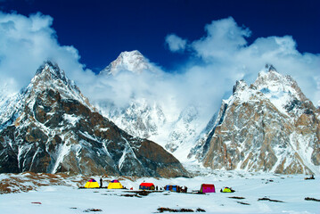 Tourist camp in the mountains near snow peaks with blue sky and beautiful clouds. Winter tourism in...