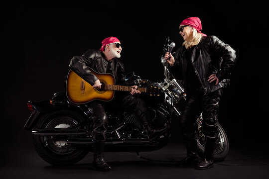 Photo of two people old bikers man lady duet chopper moto rock festival meeting play guitar sing songs youth years popular group wear rocker leather jacket isolated black color background