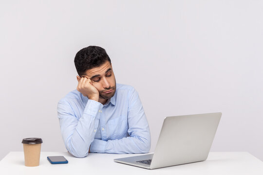 Upset lazy inefficient man employee sitting office workplace, looking at laptop screen with indifferent expression, having tedious online conversation. indoor studio shot isolated on white background