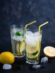 Fototapeta na wymiar A glass of summer lemonade with lemon, mint, ice on a dark concrete table