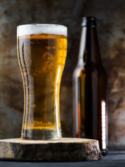 A glass of light beer on a dark background