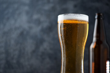 A glass of light beer on a dark background copy space