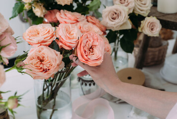 Hands of young woman florist creating bouquet of pink roses