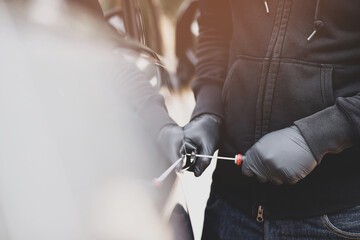 Close up car thief hand holding screwdriver tamper yank and glove black stealing automobile trying door handle to see if vehicle is unlocked  trying to break into inside. 