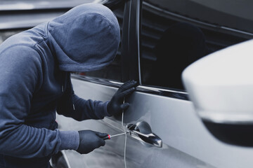 Close up car thief hand holding screwdriver tamper yank and glove black stealing automobile trying...