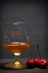 red cherries and a wine glass on a dark background