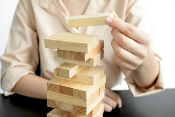 Hands of businesswomen playing wooden block game. Concept Risk of management and strategy plans for business growth and success