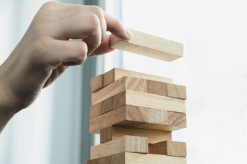 Hands of businesswomen playing wooden block game. Concept Risk of management and strategy plans for business growth and success