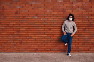 Fototapeta na wymiar Relaxed man in mask leaning on wall