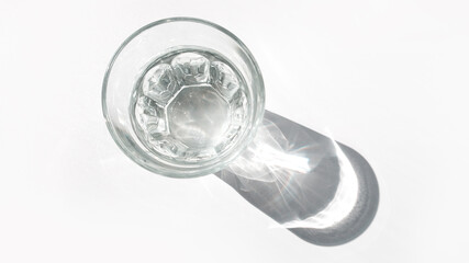 Glass cup with water with hard shadows on a white background. The concept of minimalism.