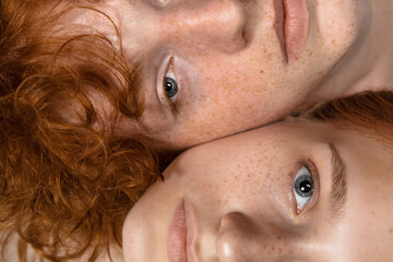 Faces. Fashion portrait of beautiful redhead couple isolated on grey studio background. Concept of...
