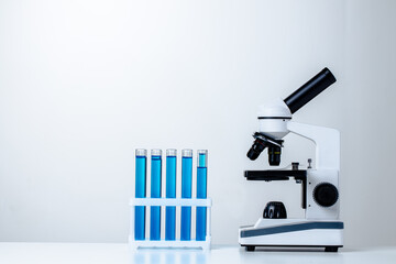 Close up of laboratory microscope with set of test tubes with blue liquid